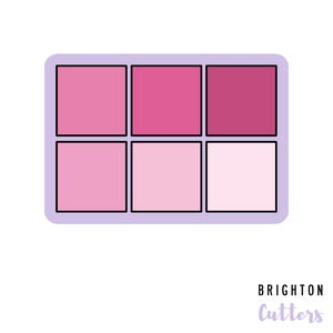 May include: A six-pan eyeshadow palette with a purple border. The eyeshadows are in shades of pink.