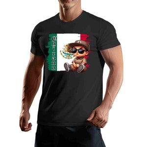 Op de afbeelding: Zwart T-shirt met een cartoonillustratie van een jonge jongen die een zonnebril en een baseballpet draagt, zittend voor een Mexicaanse vlag met het woord "Chicano" verticaal geschreven aan de linkerkant van de vlag.
