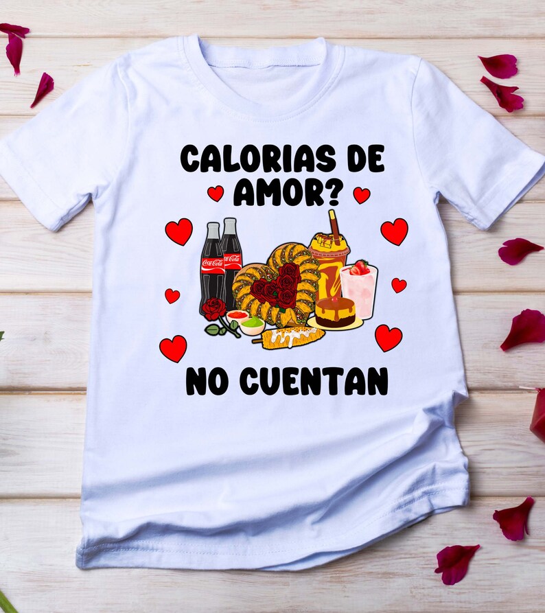 May include: White t-shirt with a graphic design featuring the text "Calorias de amor? No cuentan" in black. The graphic also includes a heart shape made of various Mexican foods, including churros, corn on the cob, and a glass of horchata.