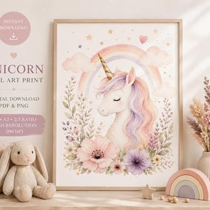 Könnte beinhalten: Ein gerahmter Aquarelldruck mit einem Einhorn mit goldenem Horn, umgeben von Blumen, einem Regenbogen und Wolken. Der Druck trägt den Text "UNICORN WALL ART PRINT" und "DIGITAL DOWNLOAD PDF & PNG". Ein Plüschhase und ein Holzregenbogen sind im Vordergrund.