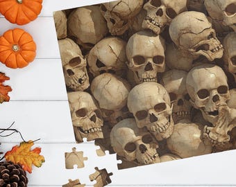 May include: A Halloween-themed puzzle featuring a detailed image of numerous human skulls. The puzzle is partially assembled, with a few pieces separate. Two small orange pumpkins and autumn leaves are on the left side, creating a seasonal display.