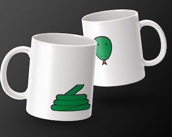 May include: Two white ceramic mugs with a green snake design. One mug features a coiled snake, while the other displays a snake head with a red tongue. The mugs have a glossy finish and a curved handle.
