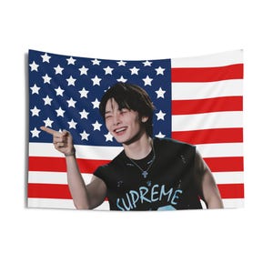 May include: A rectangular tapestry featuring a smiling person pointing to the left. The background is the American flag. The person is wearing a black sleeveless shirt with the word "SUPREME" in light blue.