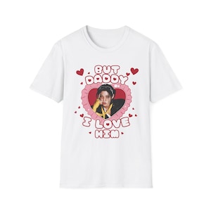 May include: White t-shirt featuring a heart-shaped graphic with the text "BUT DADDY I LOVE HIM." The graphic includes a portrait of a person. Red hearts are scattered around the main design.