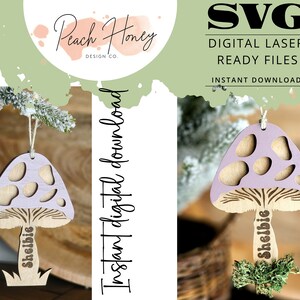 Op de afbeelding: Een digitaal downloadbaar SVG-bestand voor een lasergesneden paddenstoelversiering. De paddenstoel is paars met witte stippen en heeft de naam "Shelbie" op de steel. De versiering is klaar om te worden gepersonaliseerd met een naam.