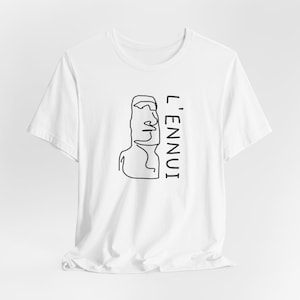 May include: White t-shirt with a black line drawing of a moai statue and the text "L'ENNUUI" printed on the front.