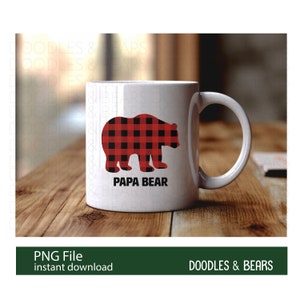 Op de afbeelding: Een witte keramische mok met een silhouet van een beer in rood en zwart buffalo plaid en de tekst "Papa Bear".