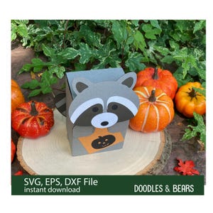 Halloween Raccoon Favor Treat Box - This Favor Treat Box has a cute gray raccoon with gray and white mask holding an orange bag with jack-o-lantern for trick-or-treating. Digital download SVG cut file for use with Cricut or Silhouette machines.