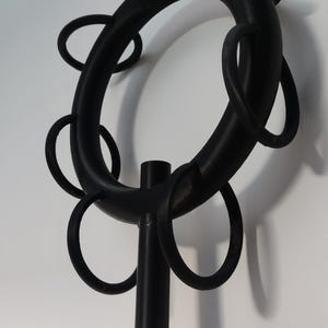 May include: Black metal coat rack with a circular top and multiple hooks. The rack has a tall, cylindrical base.