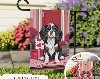 May include: A Valentine's Day garden flag featuring a cartoon Cavalier King Charles Spaniel dog sitting on a porch with a red door. The flag has a pink background with red hearts and the text "Happy Valentine's Day".