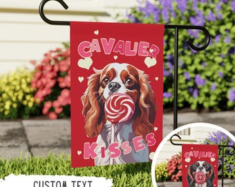 May include: A red garden flag with a Cavalier King Charles Spaniel dog illustration. The dog is holding a red and white lollipop in its mouth. The text "Cavalier Kisses" is printed on the flag in pink letters.