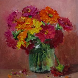 May include: An oil painting of a bouquet of zinnias in a clear glass vase. The flowers are in shades of pink, orange, and yellow, with green stems. The background is a solid pink color. The artist's signature is in the bottom left corner.
