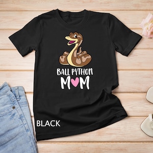 Peut inclure: T-shirt noir avec un python royal dessiné et le texte "Ball Python Mom" avec un cœur rose.