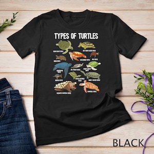 Puede incluir: Camiseta negra con un gráfico de diferentes tipos de tortugas, incluyendo la tortuga mordedora de aligátor, la tortuga de orejas rojas y la tortuga boba. El texto "TYPES OF TURTLES" está en la parte superior del gráfico.