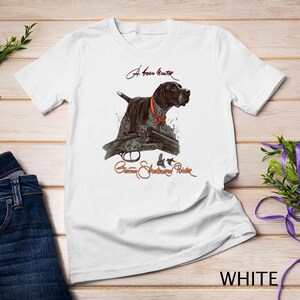Op de afbeelding: Wit T-shirt met een illustratie van een bruin-zwarte Duitse Korthaar hond. De hond wijst met zijn neus omhoog en draagt een rood-witte halsband. De tekst "A born hunter" en "German Shorthaired Pointer" staat op het T-shirt gedrukt.