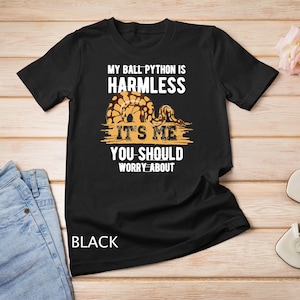 May include: Black t-shirt with a graphic of a ball python and the text "My ball python is harmless it's me you should worry about".