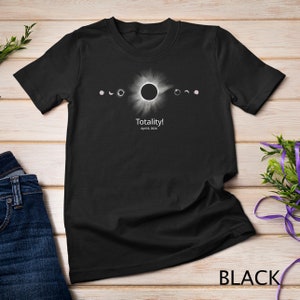 Op de afbeelding: Zwart T-shirt met een afbeelding van een zonsverduistering en de tekst "Totality! April 8, 2024".