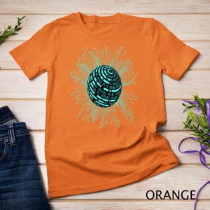 Puede incluir: Camiseta naranja con un gr&aacute;fico de una esfera azul y negra rodeada de l&iacute;neas de placa de circuito. La esfera tiene c&oacute;digo binario.