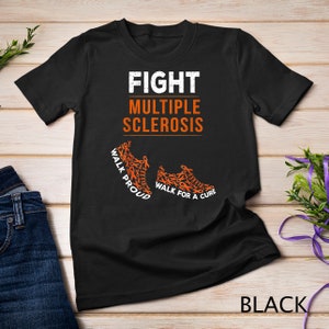 Op de afbeelding: Zwart T-shirt met de tekst "FIGHT MULTIPLE SCLEROSIS" en twee oranje sneakers gemaakt van oranje bewustzijn lintjes. De tekst op de sneakers luidt "WALK PROUD" en "WALK FOR A CURE".