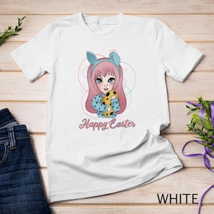 May include: White t-shirt with a cartoon illustration of a girl with pink hair holding an Easter egg. The text "Happy Easter" is printed below the illustration.