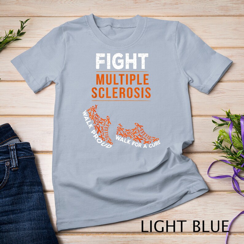 Op de afbeelding: Lichtblauw T-shirt met de tekst "FIGHT MULTIPLE SCLEROSIS" en twee oranje hardloopschoenen gemaakt van oranje bewustzijn lintjes. De tekst op de schoenen luidt "WALK PROUD" en "WALK FOR A CURE".