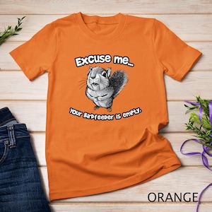 May include: Orange t-shirt with a cartoon squirrel and the text "Excuse me... your birdfeeder is empty."