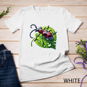 Pode incluir: Camiseta branca com um besouro vermelho e preto em uma folha verde com gotas de água. O besouro tem pernas e antenas pretas.