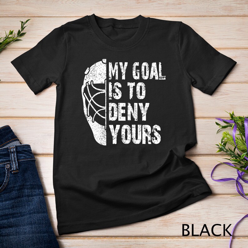 May include: Black t-shirt with a white hockey goalie mask graphic and the text "My goal is to deny yours".