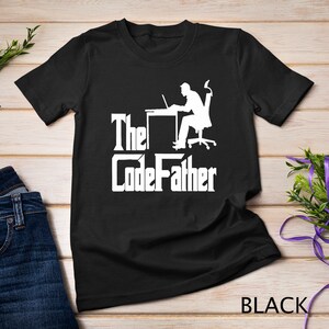 May include: Black t-shirt with a white graphic of a person sitting at a desk with a laptop and the text "The CodeFather".