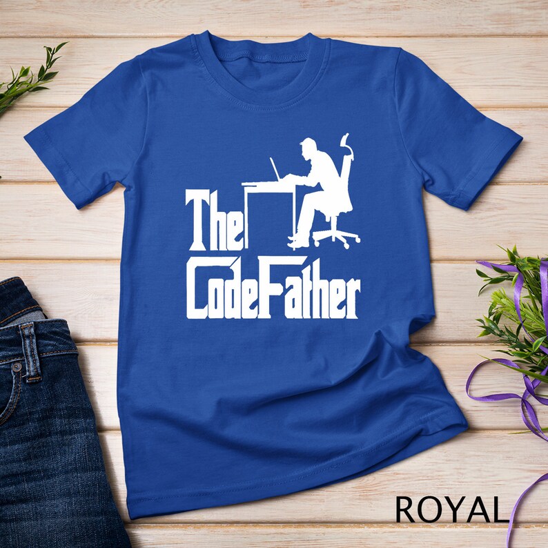 May include: A royal blue t-shirt with a white silhouette of a person sitting at a desk with a laptop. The text "The CodeFather" is printed in white below the silhouette.