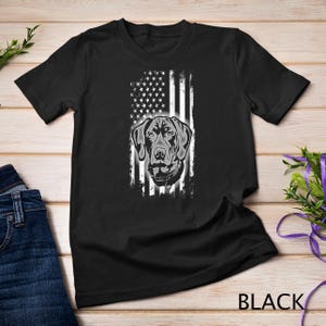 May include: Black t-shirt with a white graphic of a dog's head in front of an American flag.