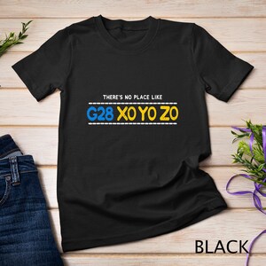 Puede incluir: Camiseta negra con el texto "THERE'S NO PLACE LIKE G28 XO YO ZO" en letras amarillas y azules.