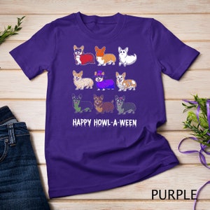 Può includere: Maglietta viola con un'immagine di nove corgi vestiti con costumi di Halloween. Il testo "HAPPY HOWL-A-WEEN" è stampato sotto i corgi.