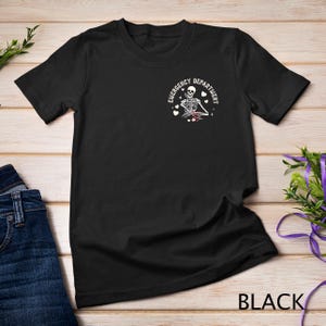 May include: Black t-shirt with a white skeleton graphic and the text "Emergency Department" with hearts around the graphic.