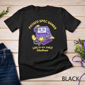 May include: Black t-shirt with a cartoon computer graphic. The graphic features a purple computer with a face, keyboard, and mouse, with the text "POTATO SPEC GAMER" and "LAG IS MY ONLY Weakness".