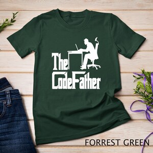 May include: A dark green t-shirt with a white silhouette of a person sitting at a desk with a laptop. The text "The CodeFather" is printed in white below the silhouette.