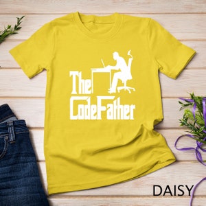 May include: Yellow t-shirt with a white silhouette of a person sitting at a desk with a laptop and the text "The CodeFather".