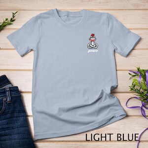 May include: Light blue t-shirt with a graphic of a sock monkey meditating with the word "peace" underneath.