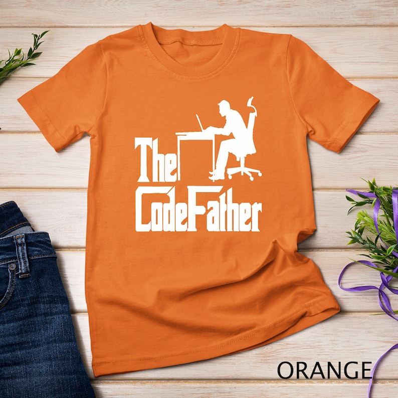 May include: Orange t-shirt with a white silhouette of a person sitting at a desk with a laptop and the text "The CodeFather" in a bold, white font.