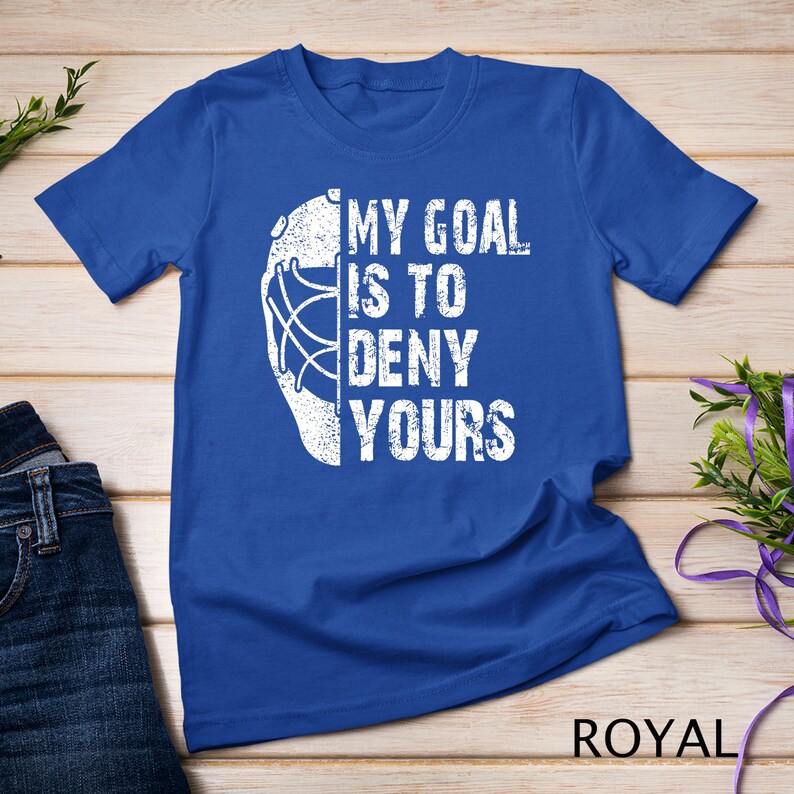 May include: A royal blue t-shirt featuring a white hockey goalie mask and the text "My goal is to deny yours".