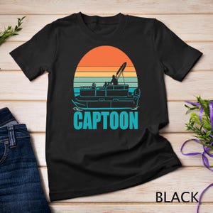 May include: Black t-shirt with a retro sunset graphic of a pontoon boat with the text "CAPTOON" in blue.