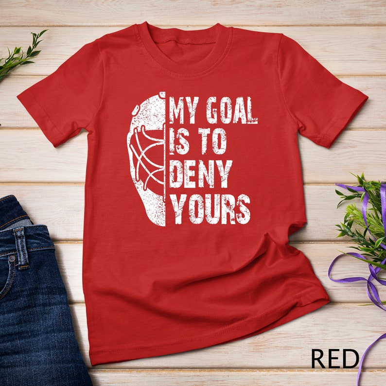 May include: Red t-shirt with a white hockey goalie mask graphic and the text "My goal is to deny yours".