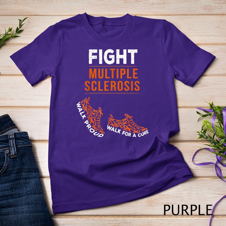 Op de afbeelding: Paars T-shirt met de tekst "FIGHT MULTIPLE SCLEROSIS" in wit. Het shirt heeft twee oranje hardloopschoenen gemaakt van oranje bewustzijnslintjes met de tekst "WALK PROUD" en "WALK FOR A CURE".