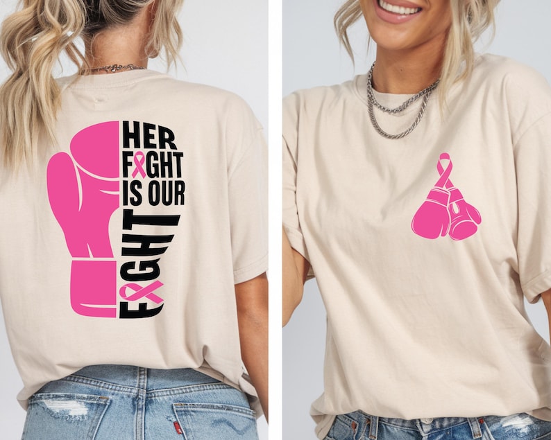 Pode incluir: Camiseta bege com um gr&aacute;fico de luva de boxe rosa e o texto "HER FIGHT IS OUR FIGHT" nas costas. A frente da camisa apresenta um par de luvas de boxe rosa. A camisa &eacute; feita de um material macio.