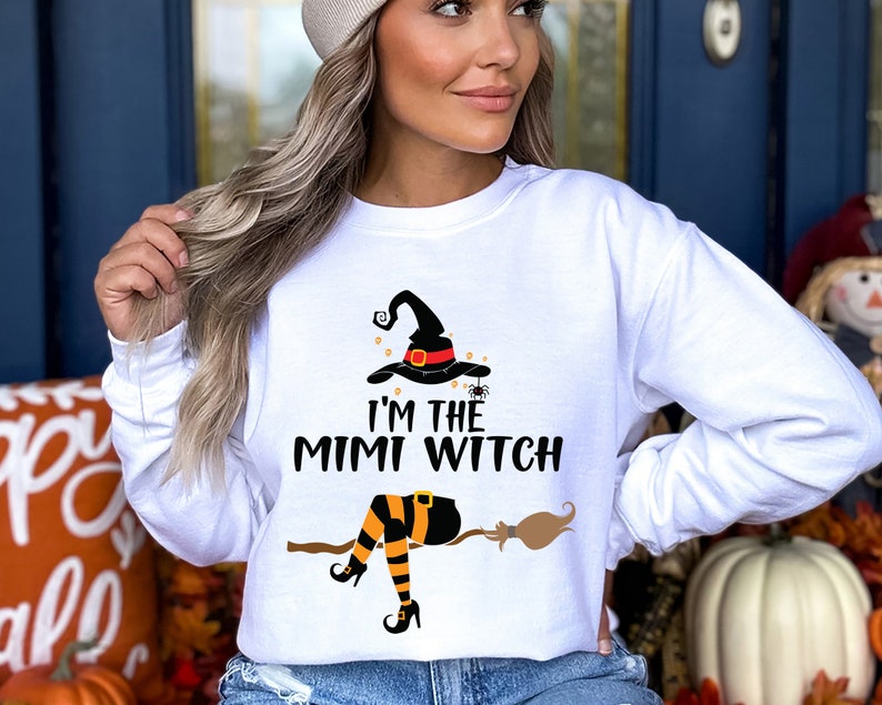May include: White long-sleeve sweatshirt with a black witch graphic and the text "I'm the Mimi Witch".