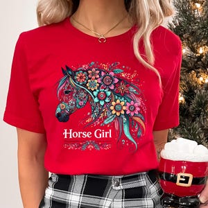 Puede incluir: Camiseta roja con un dise&ntilde;o de caballo floral colorido y el texto "Horse Girl" impreso en la parte delantera.