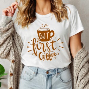 May include: White t-shirt with a brown coffee cup graphic and the text "BUT first Coffee". The shirt is made of a soft material and is suitable for casual wear.