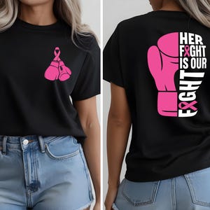 Pode incluir: Camiseta preta com luvas de boxe rosa e uma fita rosa na frente. A parte de tr&aacute;s da camisa apresenta um design de luva de boxe rosa com as palavras "HER FIGHT IS OUR FIGHT" em branco e rosa.