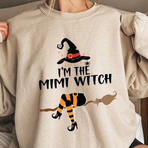 May include: A beige sweatshirt with a black and orange witch graphic and the text "I'm the Mimi Witch".