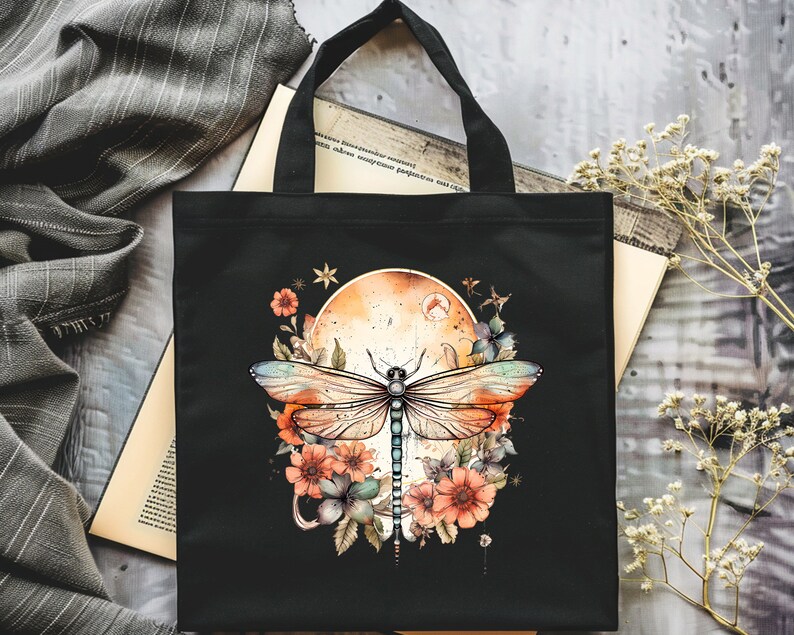 Pu&ograve; includere: Borsa tote nera con un design di libellula e fiori colorati. La libellula ha ali blu, verdi e arancioni. I fiori sono arancioni, rosa e bianchi. Lo sfondo &egrave; una tela nera con una luna in stile acquerello.